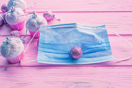 Pink Christmas balls background and a protective mask. Christmas toys on a pink background