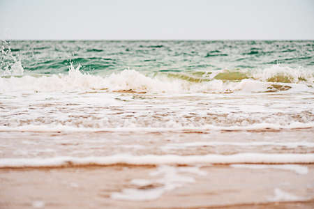 Sea in cloudy warm weather with blue sky. Sea waves and sand in summer.の写真素材