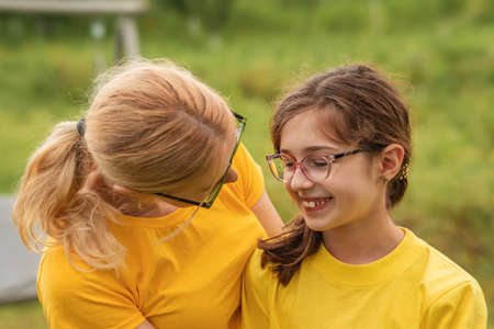 Mother and teenage daughter outside. Teenager girl and mom in yellow t-shirts. Family good relationsの写真素材