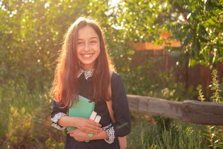Schoolgirl teenager girl smiling with notepad and backpack. pretty young girl with a backpack.の写真素材