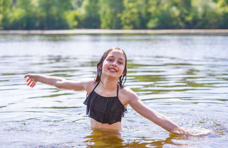 Happy child bathes. Teenage girl swims in the river in summer.の写真素材