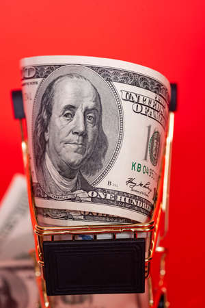 Banks, finance. Money in a gold-colored shopping cart on a bright red background.の写真素材