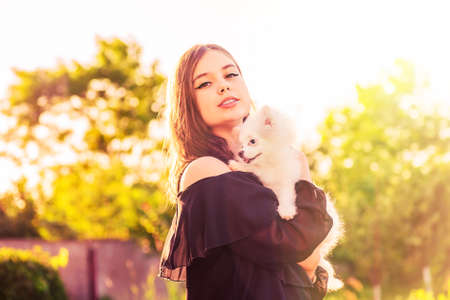 A teenage girl and a spitz puppy. Beautiful brunette girl with her dog in her arms.の写真素材