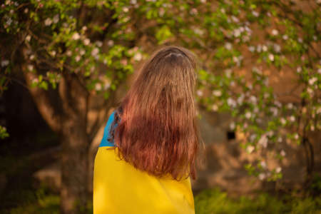 Teen girl is standing with the Ukrainian flag. Yellow and blue fabric.の写真素材
