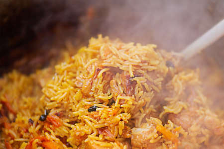 Pilaf cooked on a fire. Preparation of pilaf dish close-up.の写真素材