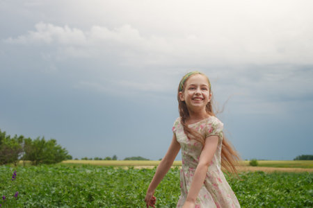 The joy of a child. A little girl in a flower dress against the background of rural nature.の写真素材
