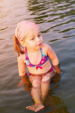 A little girl is swimming in the river. A child in a swimsuit in the summer on vacation.の写真素材