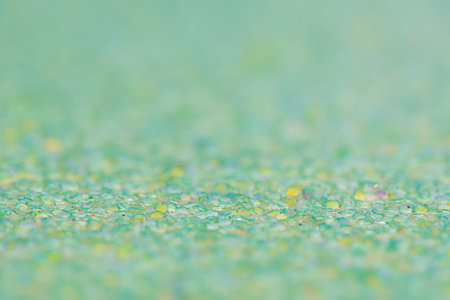 Macro photo of glitter paper. Green background with a thin focal part and a main part in defocus.の写真素材