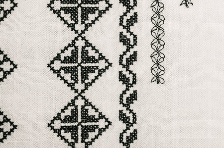 Macro photo of a part of the embroidery. Light natural fabric with black embroidery.の写真素材