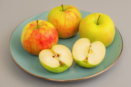Red and green apples, whole and cut in half, in a plate on a background. Apple, vitamin.の写真素材