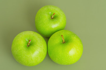 Three ripe green apples on a green background. Apples, fruits. Top viewの写真素材