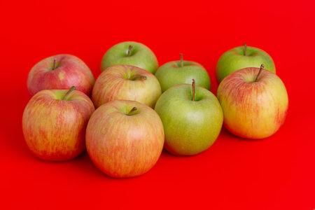 Apples on a red background. Red with yellow and green apples