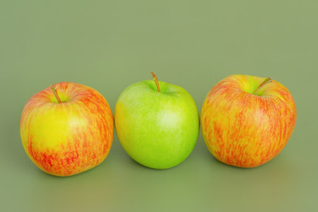 Two red and yellow apples and one green apple. Fruit, apples on a green background
