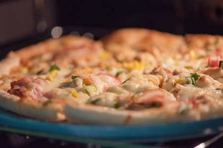 Ready-made pizza with bacon and cheese on a blue plateの写真素材