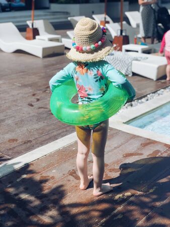 Girl 3 years old standing at swimming pool. Kid ready to swim. Using swim ring. Happy summer vacation fun tourist enjoying travel holidays. Funny holiday concept. Kid sport activity.の写真素材