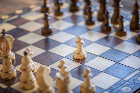 White and black wooden pieces on a chessboard. Chessboard installed during the game.の写真素材