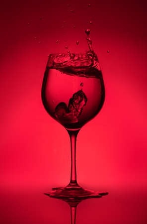 Splash of water in a glass on a red background. Unusual sculpturesの写真素材