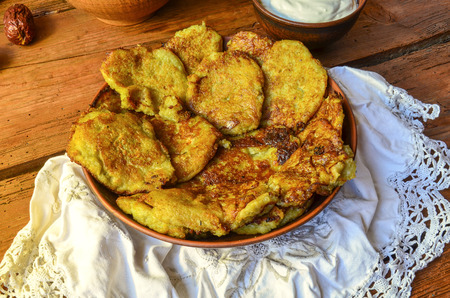 Plate with tasty potato pancakes on wooden rustic  table. Potato pancakes or latkes served with sour creamの写真素材