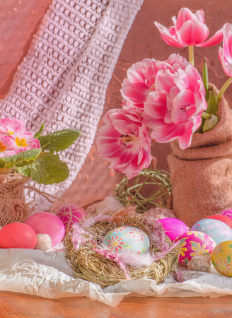 Beautiful tulips with colorful eggs in nest on wooden background. Composition with Easter eggs and blooming flowersの写真素材