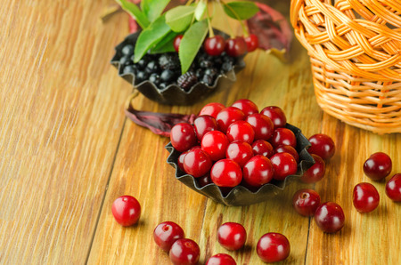 Blueberry and cherries with leaves on a old wooden table.の写真素材