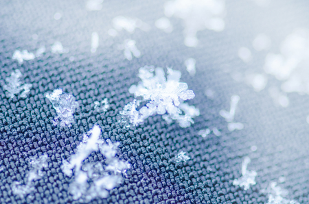 Macro photo of real snow crystal. Snowflake  on blue  background.  Fashion background with white snowflakesの写真素材