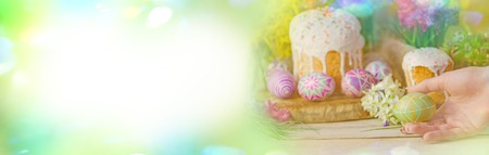 Pink and yellow bokeh Easter banner at table with Easter eggs and Easter cakes.