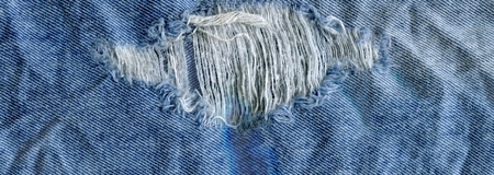 Blue torn grunge denim jeans texture. Jeans bit torn