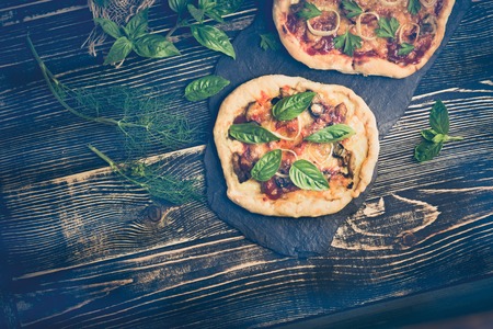 Italian pizza and pizza ingredients served on wooden background. Pizza margarita with tomatoes, olive, basil and mozzarella close up. Free space on table. Retro style tonedの写真素材