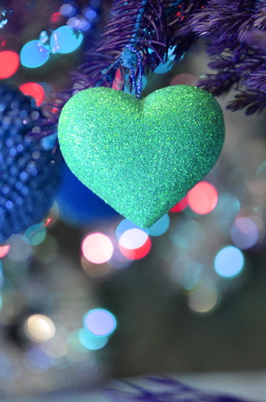 Fir tree branch with blue heart  decoration. Blue heart hanging on Christmas tree branchの写真素材