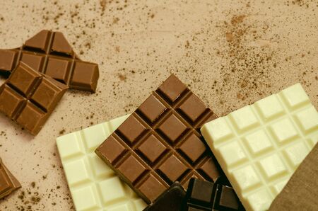 Dark, milk and white chocolate bars on wooden background. Top view with copy space
