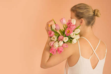 Attractive happy girl with bouquet of flowers against beige background.
Young charming  smile girl holding big bouquet of tulips on light beige background.
の写真素材