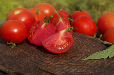 Tomato with slice on rustic wooden background. Fresh cut tomato  on wooden tableの写真素材