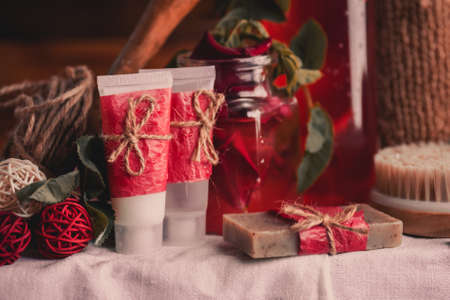 Composition with plastic bottles of body care. Red cosmetic with rose oil. Red spa set.の写真素材