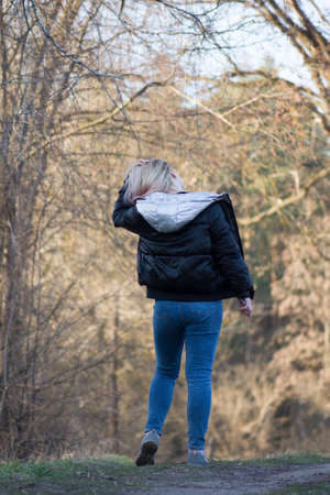 Woman walking on spring forest. Walking in the spring park. Beautiful young woman walking through the spring forest.の写真素材