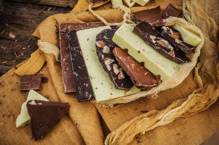 Dark, milk and white chocolate bars on wooden background. Top view with copy space