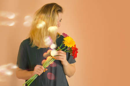 Young positive beautiful shy woman posing with bouguet of chamomile. Beautiful attractive lady...