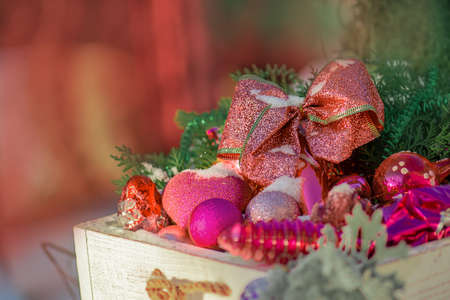 Christmas accessories and toys covered in snow in a wooden box outdoors.の写真素材