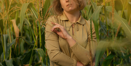 Elegance and trendy fashion at summer season outdoors. Beautiful young girl in a gold dress in a green cornfield plantation.の写真素材