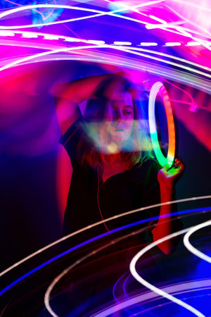 Stylish blonde girl dancing clubbing chill on background with mixed neon light. Woman in night club lights bokeh backdrop.の写真素材