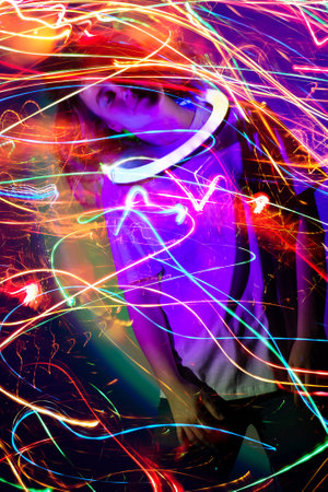 Beautiful model girl posing in neon colorful bright glow on a black backdrop. Adorable dancer dancing in neon mixed light.の写真素材