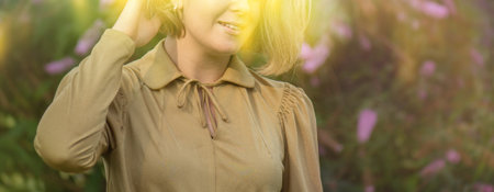 Happiness concept. Positive female model smiling to camera near the buddleia flowers. Happy woman...