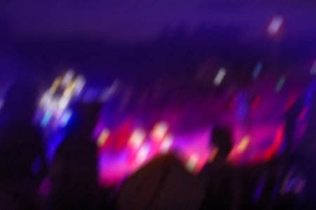 Crowd at open air rock festival at night. Blurred audience with hands raised at night music...