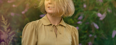 Blonde girl outdoors in butterfly bush or summer lilac. Buddleia flowers and elegant young woman.の写真素材