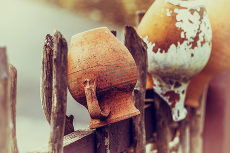 Related structure twigs and sticks in a vintage wooden rural fence with creative household items - old clay pots for cooking as trendy abstract background for designの写真素材
