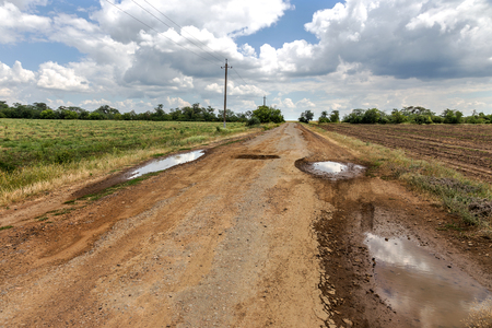 Damaged road, cracked asphalt sword with potholes and spots, Ukraine. Very bad asphalt road with large holes. Terrible technology construction roads. Numerous dangerous failures. Bad road. Road repairの写真素材