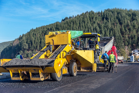 Blagoevgrad, BULGARIA - 14 November 2015: Construction workers carrying out repairs of the road in the highlands. Works of modern road construction equipment.のeditorial素材