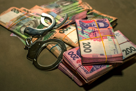 Many Ukrainian money hryvnia. Handcuffs on the money. Corruption in Ukraine. The fight against...