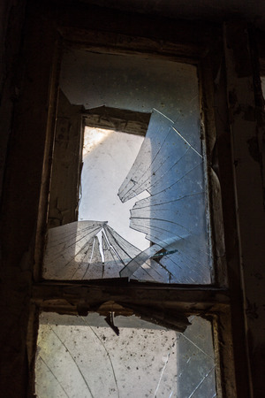Broken glass in the windows of an old abandoned mystical house. A horror picture of broken window glass. Gloomy interior, depressive background for the design of tragedy, horror, Halloweenの写真素材