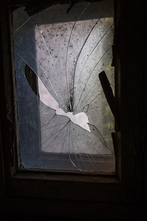 Broken glass in the windows of an old abandoned mystical house. A horror picture of broken window glass. Gloomy interior, depressive background for the design of tragedy, horror, Halloweenの写真素材