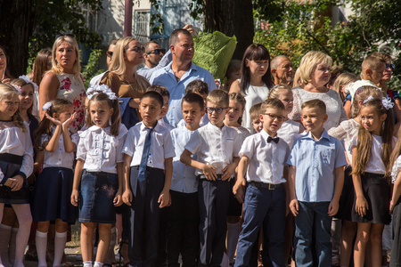 ODESSA, UKRAINE September 1, 2018: September 1, day of the celebration of knowledge. Smiling happy first graders and their happy parents. Teacher in schoolyard holiday Beginning of the training yearのeditorial素材